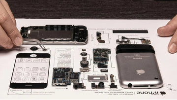 Hands arranging original phone components on a teardown art workbench