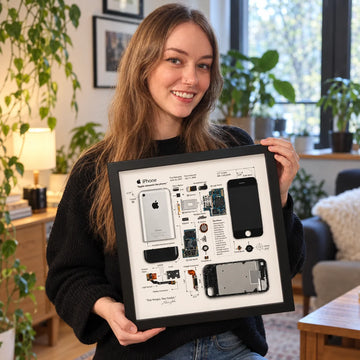 Woman displaying an iPhone 1st Generation Teardown Frame in a cozy home interior