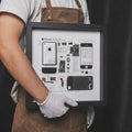 Hand holding iPhone 1 teardown frame, premium handmade smartphone disassembly art piece